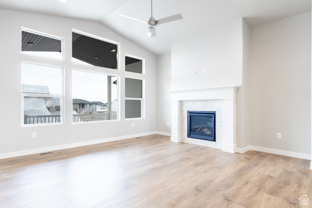 Unfurnished living room featuring baseboards, visible vents, a ceiling fan, a glass covered fireplace, and light wood-style flooring