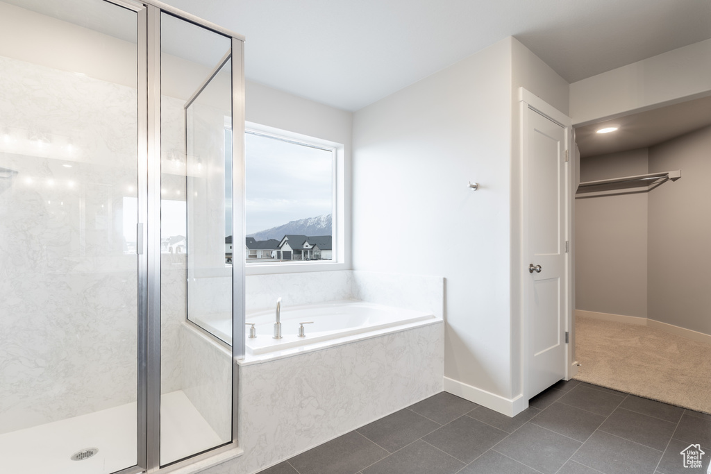 Bathroom featuring a garden tub, a shower stall, baseboards, and tile patterned floors
