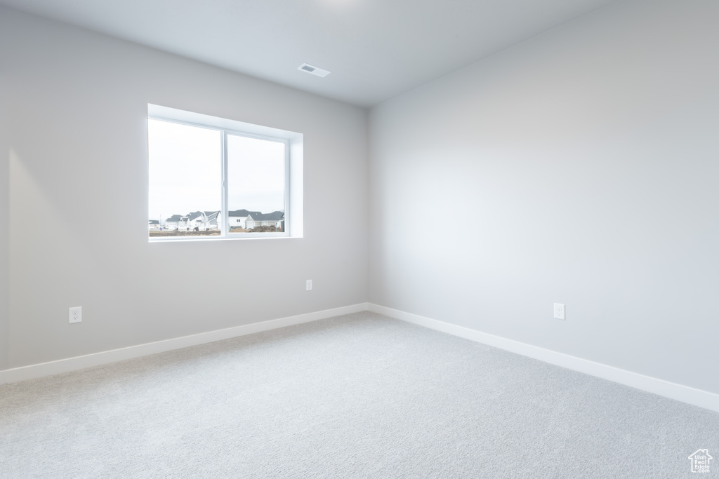 Carpeted empty room with baseboards and visible vents