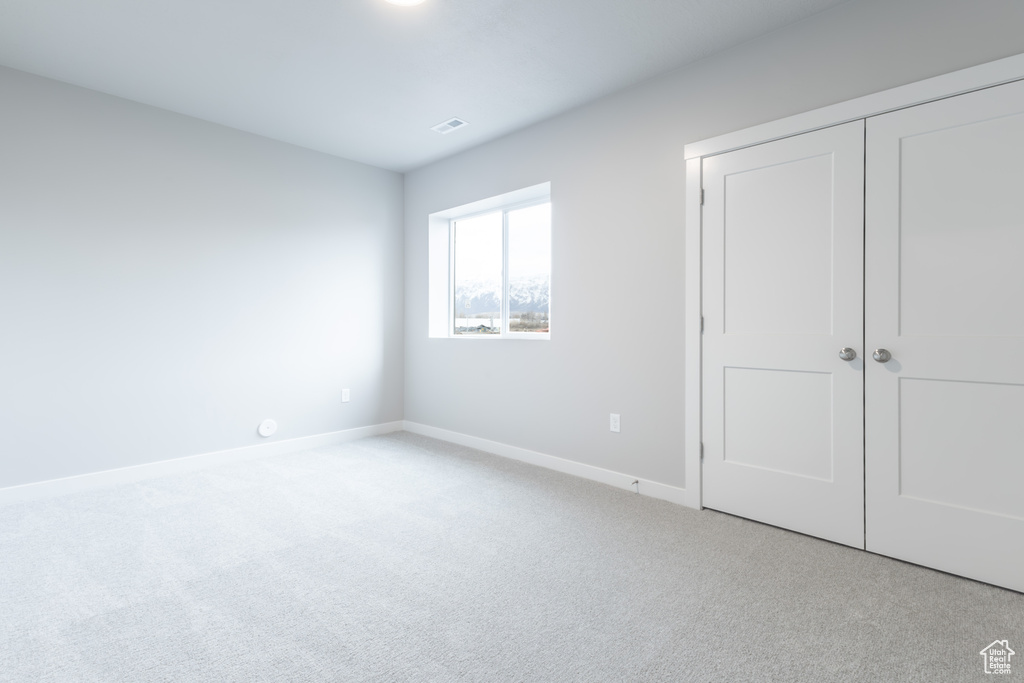 Unfurnished bedroom with visible vents, baseboards, a closet, and light colored carpet