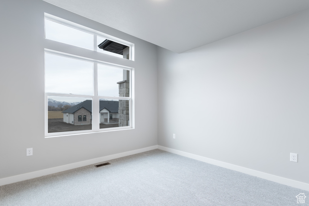 Spare room featuring a healthy amount of sunlight, visible vents, baseboards, and carpet flooring