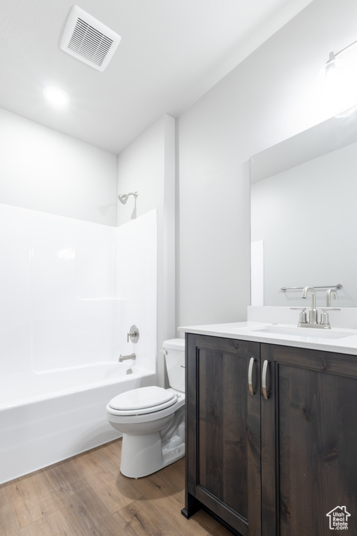 Bathroom with shower / bathtub combination, toilet, wood finished floors, vanity, and visible vents