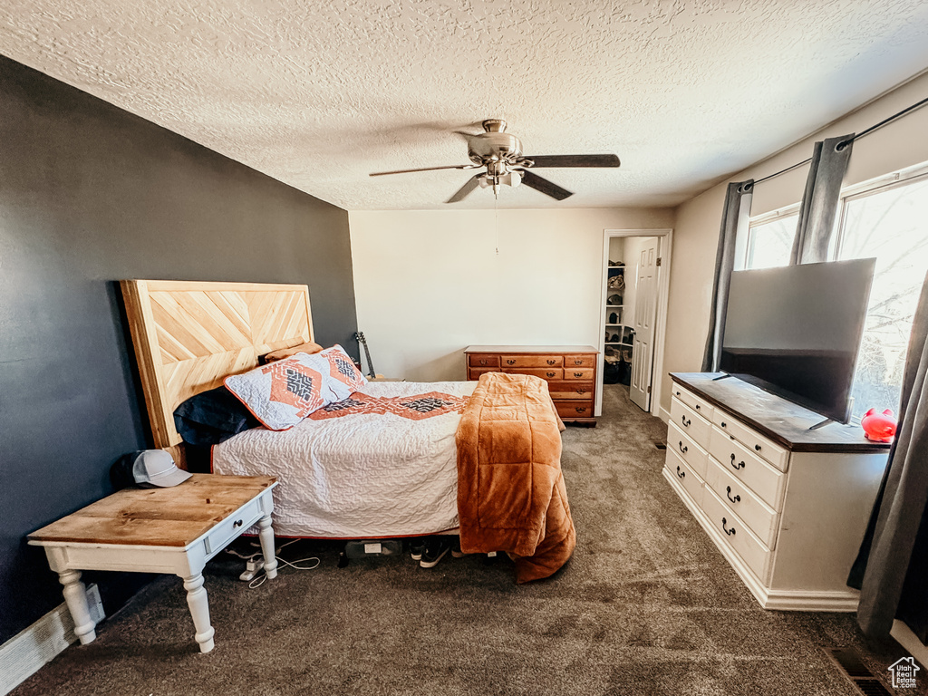 Carpeted bedroom with ceiling fan, a spacious closet, visible vents, and a textured ceiling