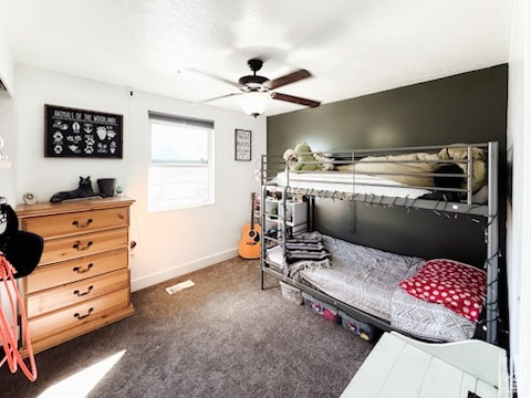Bedroom featuring ceiling fan, baseboards, and dark colored carpet