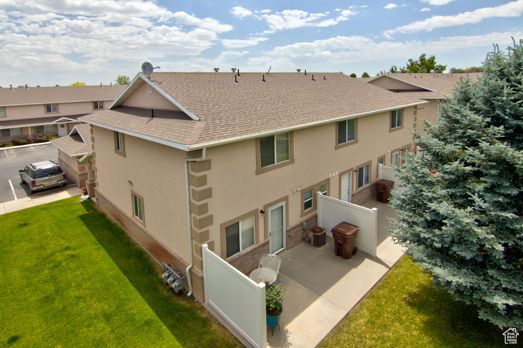 Rear view of house featuring stucco siding, a shingled roof, and a patio