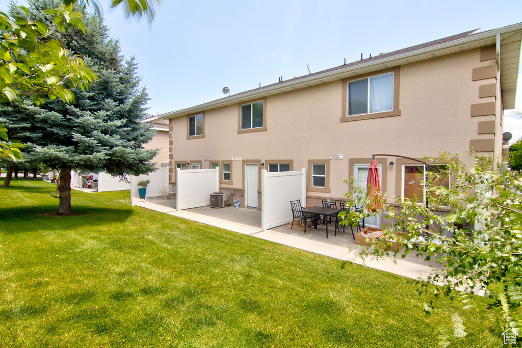 Rear view of property featuring stucco siding, a patio, and a lawn