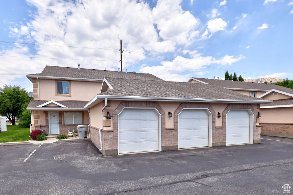 Townhome / multi-family property featuring community garages, stucco siding, and a shingled roof