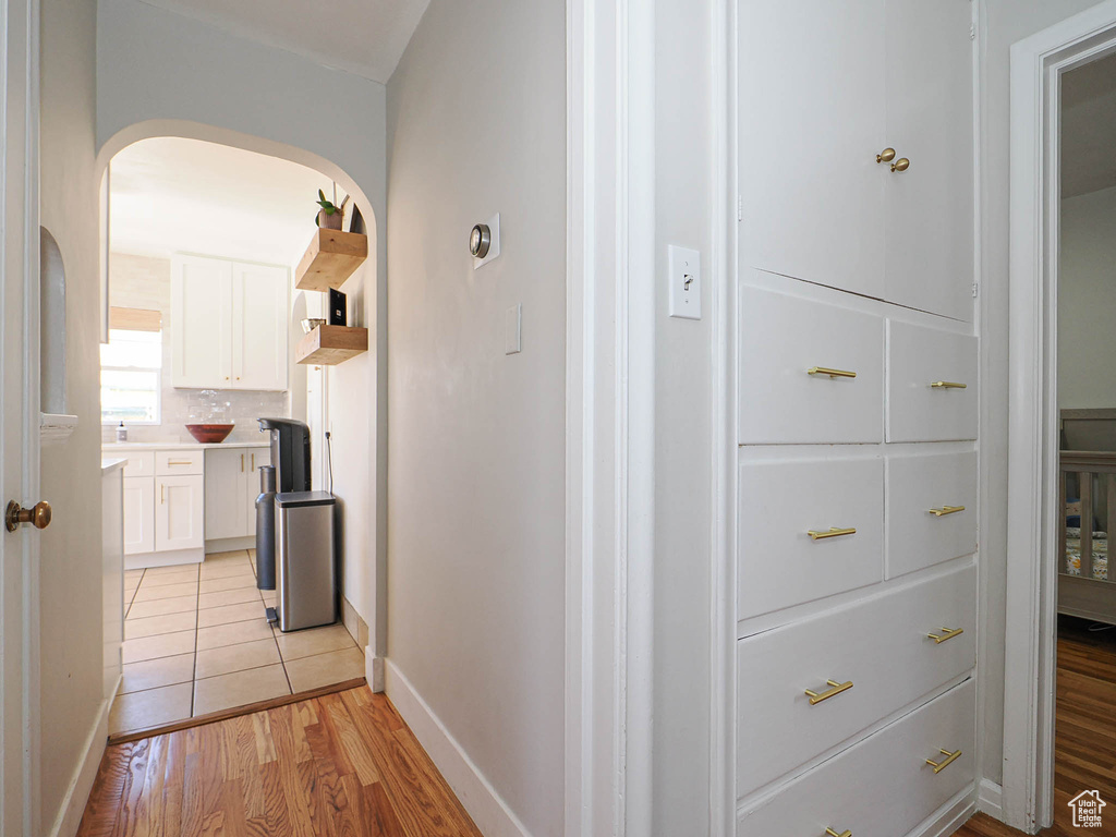 Hall featuring light wood-type flooring, arched walkways, and baseboards