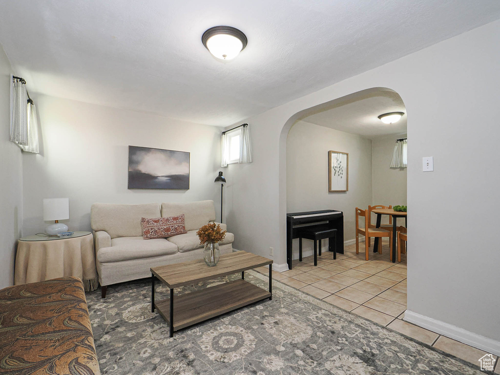 Living room with light tile patterned floors, baseboards, and arched walkways