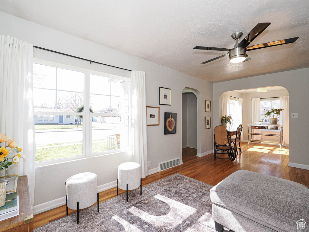 Bedroom with arched walkways, wood finished floors, visible vents, and baseboards