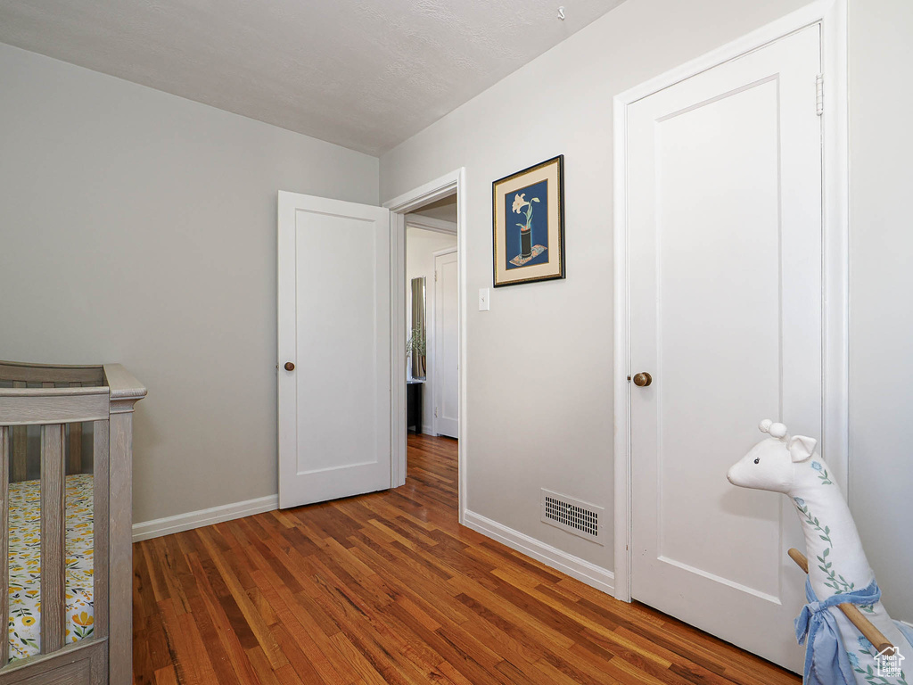 Unfurnished bedroom featuring dark wood-style flooring, visible vents, and baseboards