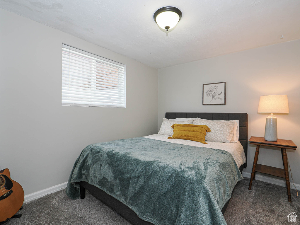 Bedroom with dark colored carpet and baseboards