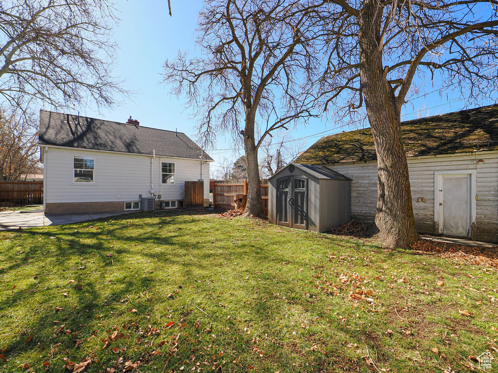 View of yard with a shed, an outdoor structure, fence, and central air condition unit