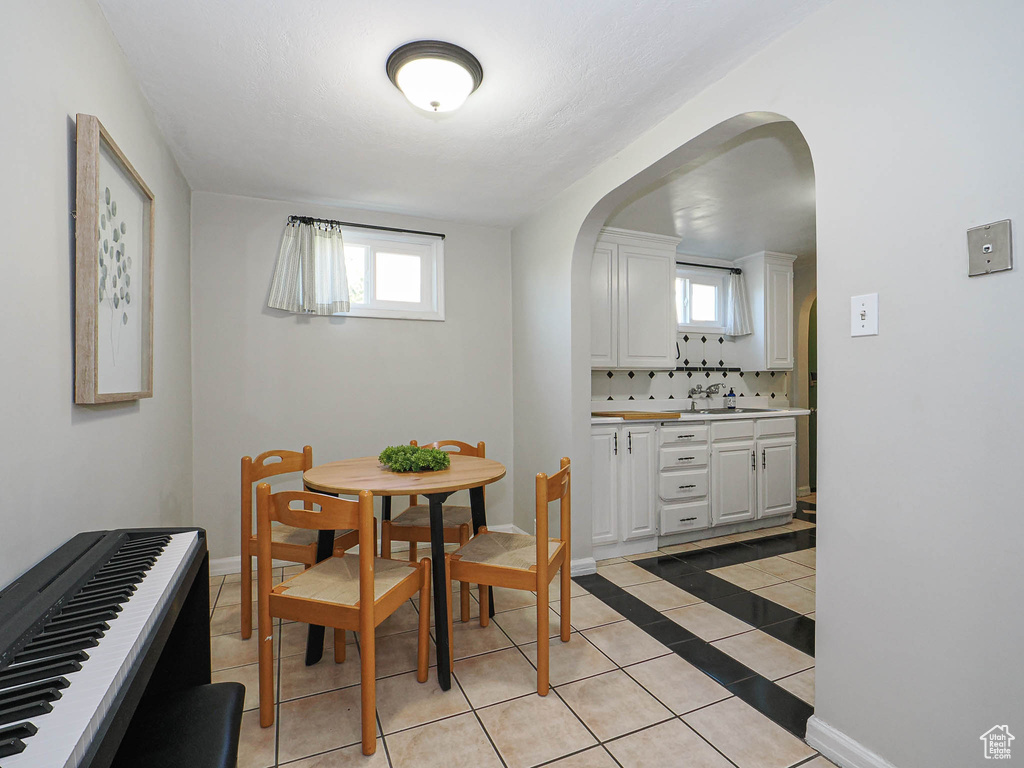 Dining area featuring arched walkways, light tile patterned floors, plenty of natural light, and baseboards