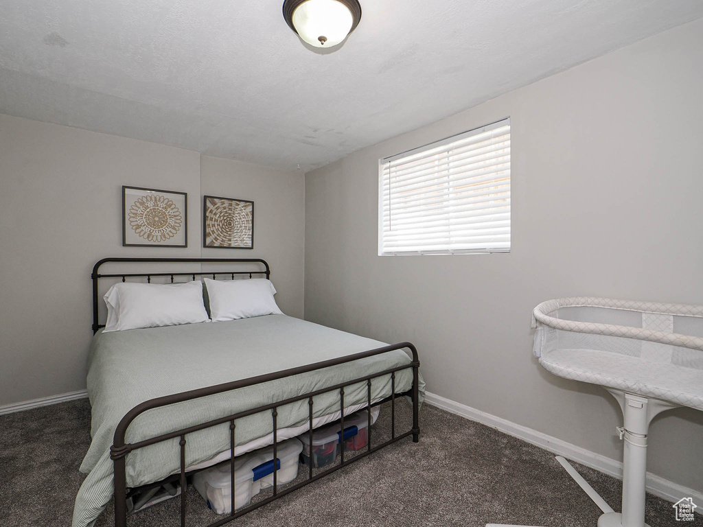 Bedroom with dark colored carpet and baseboards