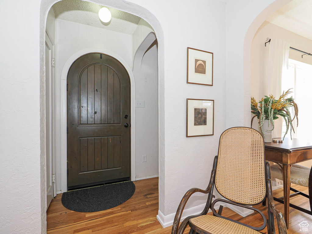 Entrance foyer with arched walkways, baseboards, and wood finished floors
