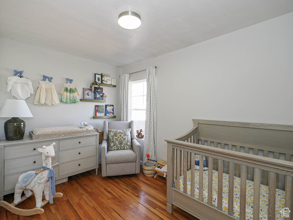 Bedroom featuring a crib and wood finished floors