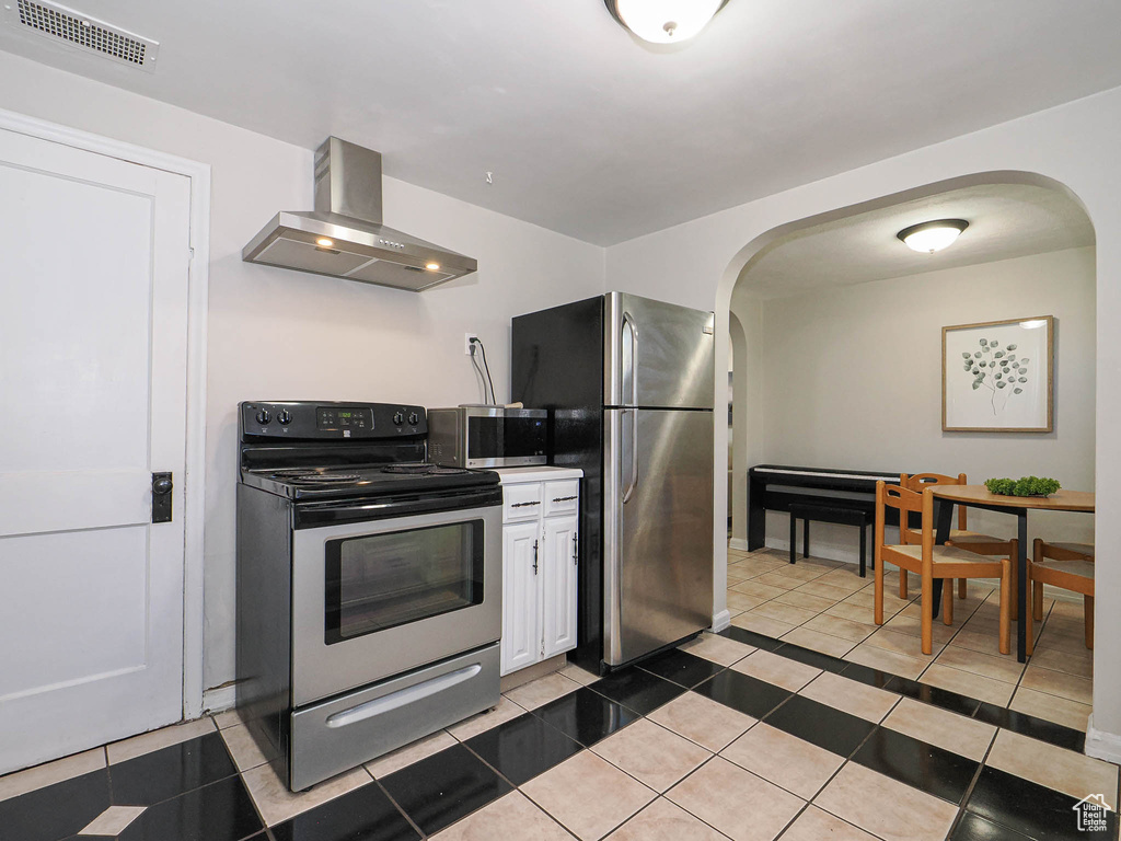 Kitchen featuring arched walkways, light tile patterned floors, visible vents, appliances with stainless steel finishes, and ventilation hood