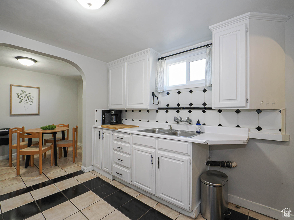 Kitchen featuring light countertops, white cabinetry, arched walkways, and light tile patterned flooring