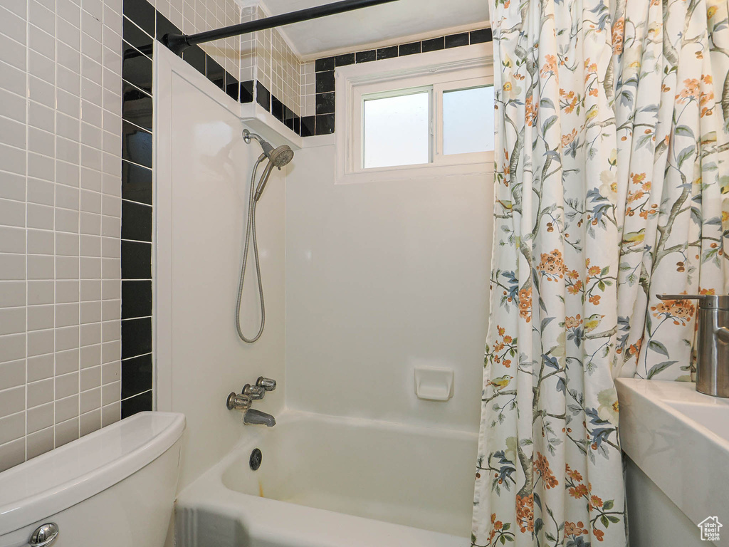 Bathroom featuring toilet and shower / bath combo with shower curtain