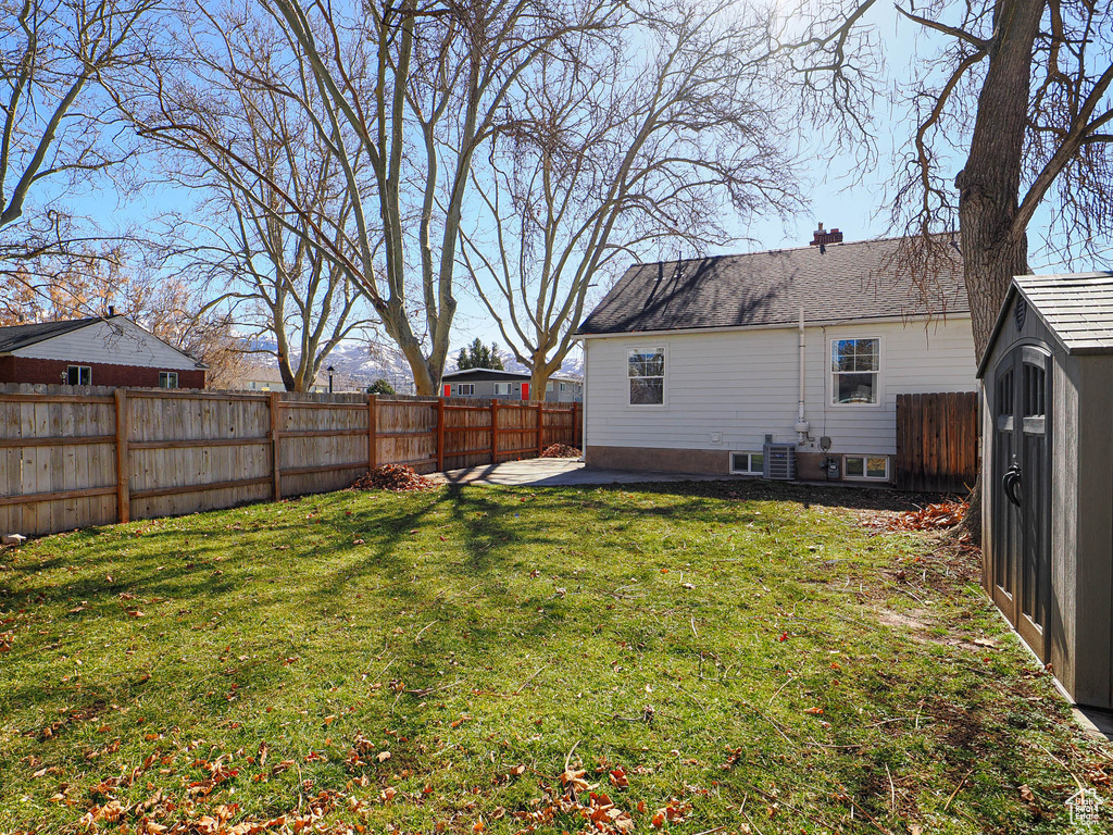 View of yard with a storage shed, a patio area, a fenced backyard, and an outbuilding
