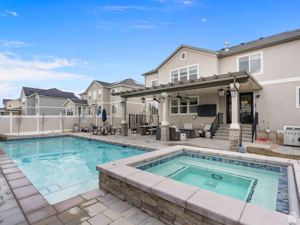 Rear view of property with a fenced in pool, a residential view, an in ground hot tub, fence, and stucco siding