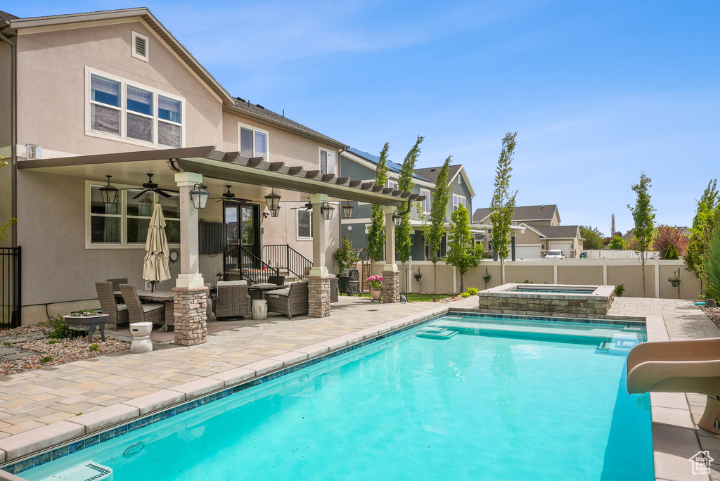 Rear view of house with ceiling fan, stucco siding, and a fenced backyard
