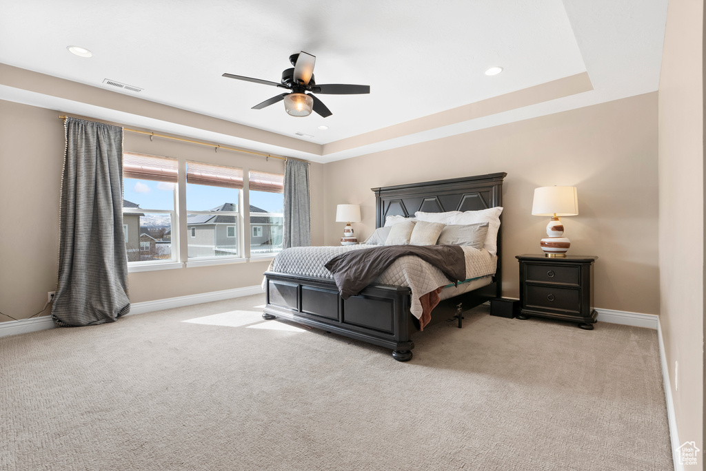 Bedroom with recessed lighting, light carpet, visible vents, baseboards, and a raised ceiling