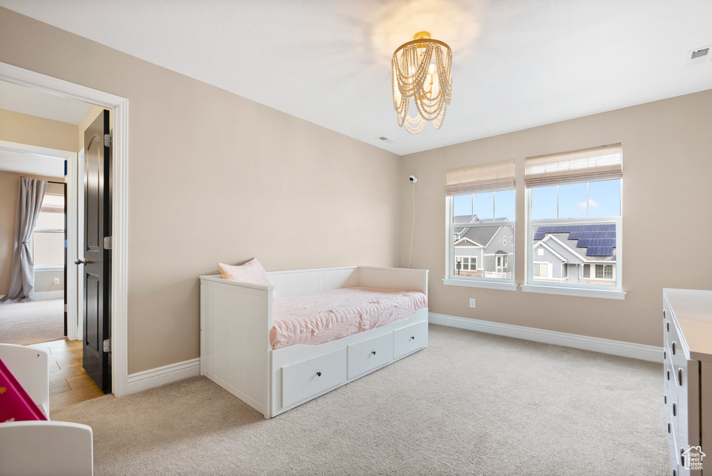 Bedroom with light carpet, multiple windows, baseboards, and a notable chandelier