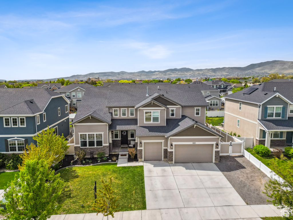 Craftsman inspired home with stone siding, a residential view, concrete driveway, a garage, and a mountain view