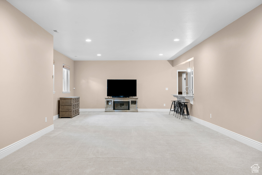 Unfurnished living room with recessed lighting, baseboards, and light colored carpet