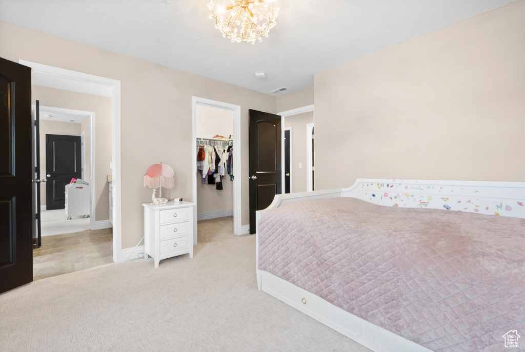 Bedroom with a chandelier, light carpet, visible vents, baseboards, and a spacious closet