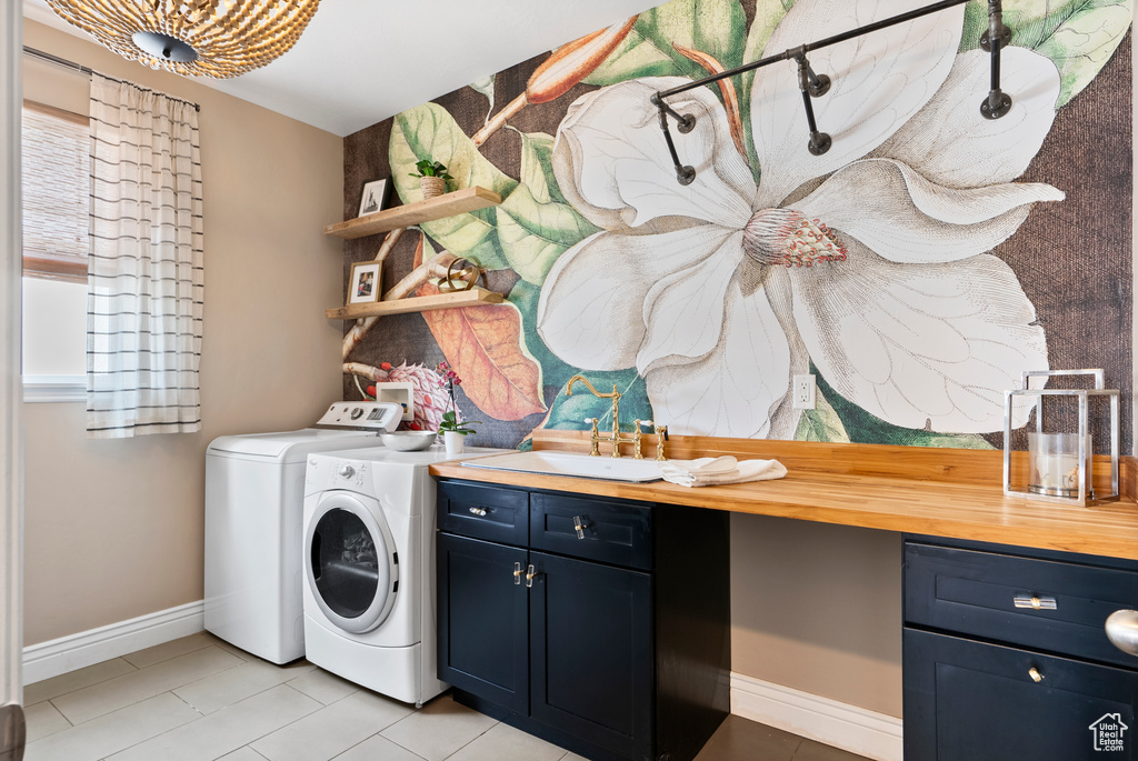 Laundry area with a sink, washing machine and dryer, cabinet space, and baseboards