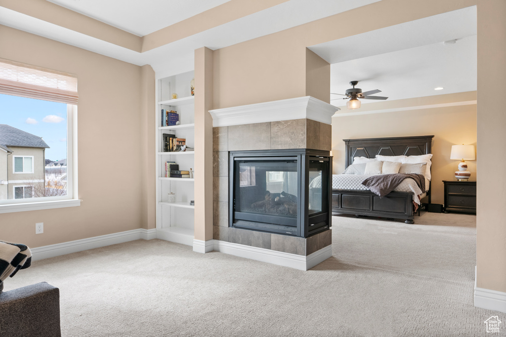 Bedroom with a tile fireplace, light colored carpet, and baseboards