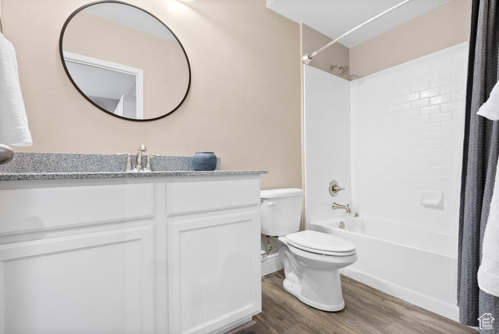 Full bathroom featuring toilet, vanity, wood finished floors, and shower / tub combination