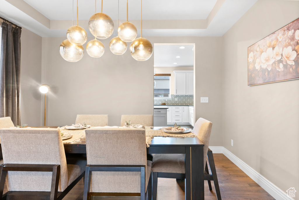 Dining space featuring a raised ceiling, dark wood finished floors, and baseboards