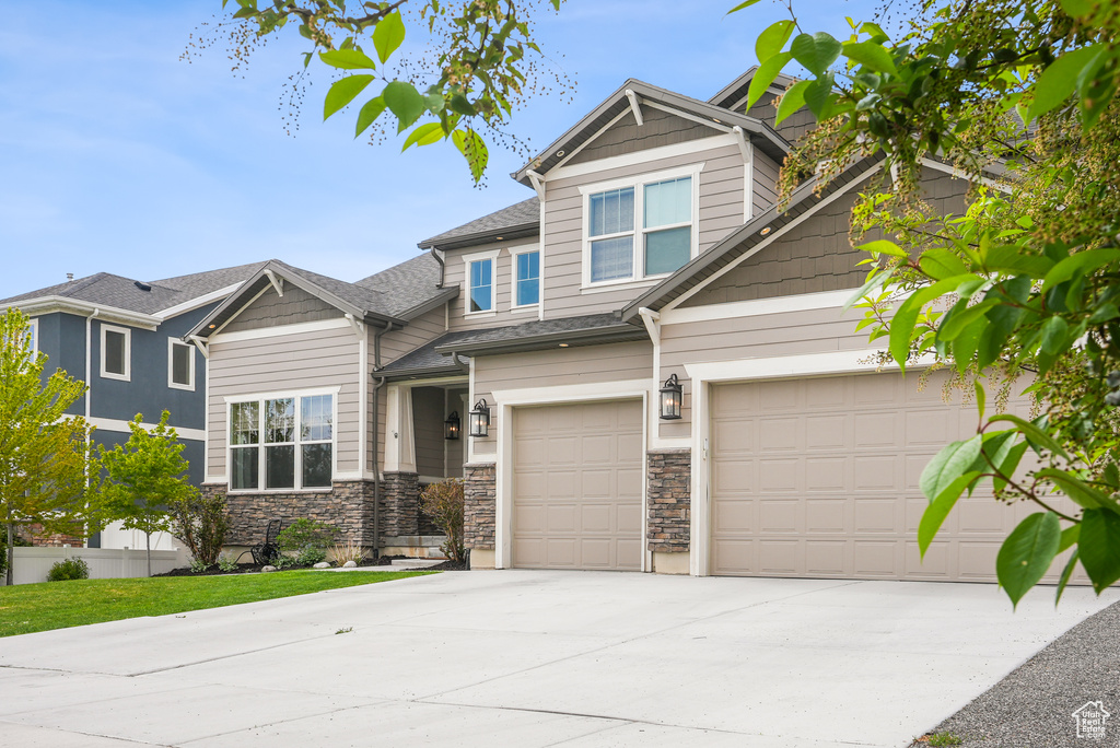 Craftsman house featuring driveway, stone siding, and an attached garage