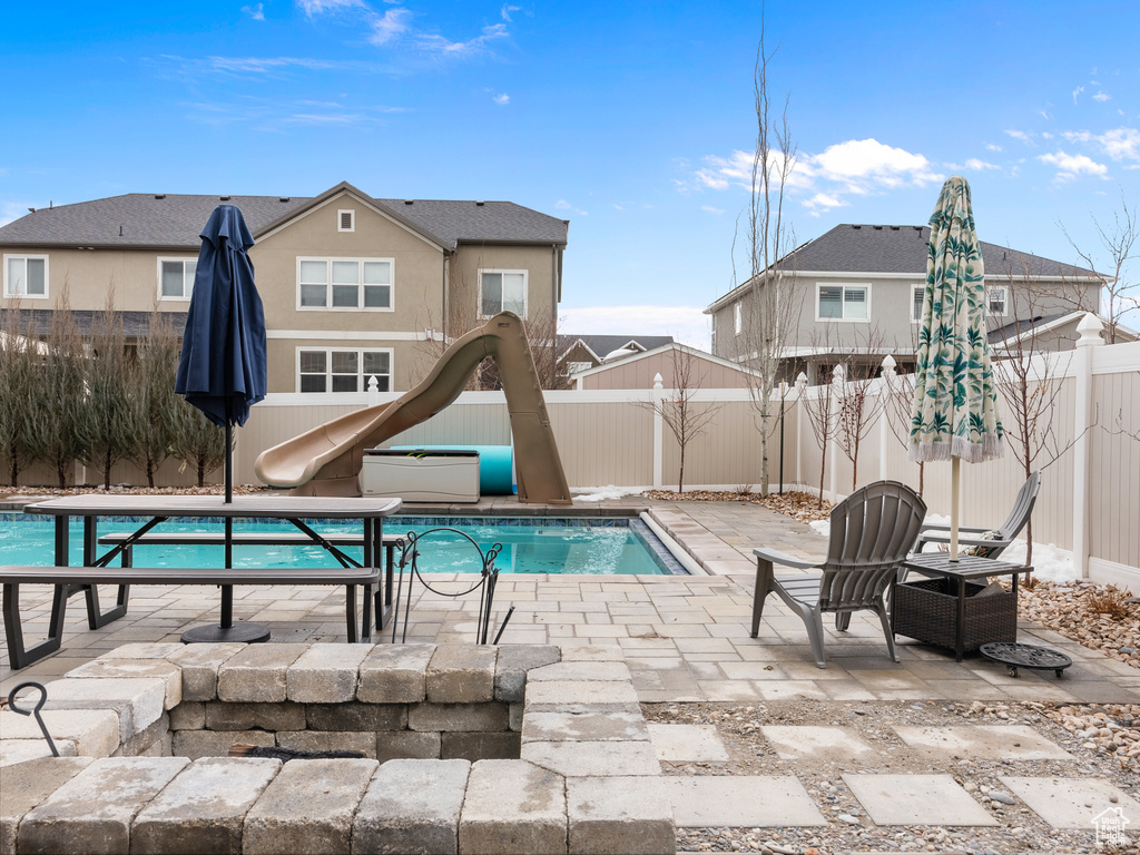 View of swimming pool with a patio, a water slide, a fenced backyard, and a fenced in pool