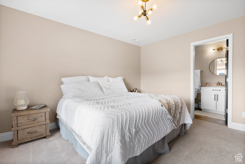 Bedroom featuring light carpet, baseboards, ensuite bathroom, a chandelier, and a sink