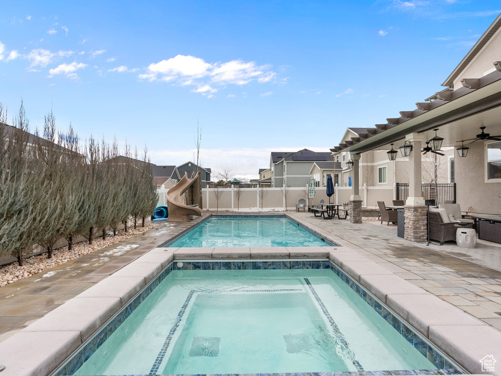 View of pool featuring a fenced in pool, a ceiling fan, a fenced backyard, an in ground hot tub, and a water slide