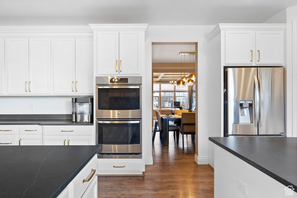 Kitchen featuring stainless steel appliances, dark countertops, and white cabinets