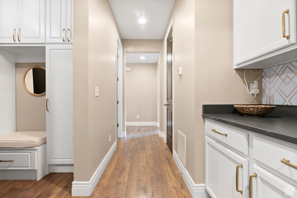 Hallway with light wood-style flooring, visible vents, baseboards, and recessed lighting