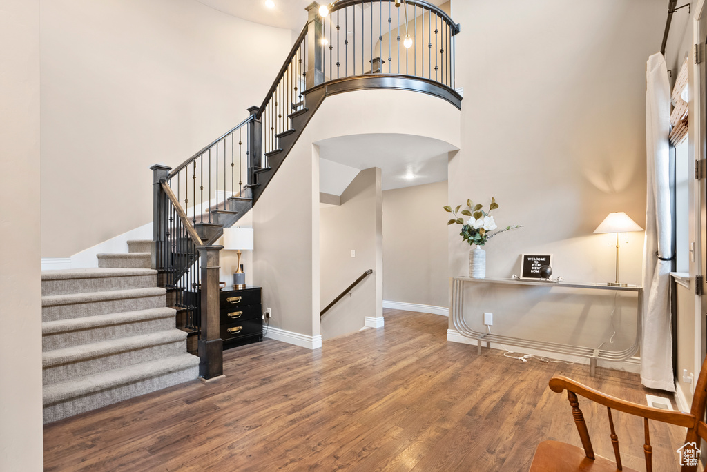 Entrance foyer featuring a high ceiling, baseboards, arched walkways, and wood finished floors