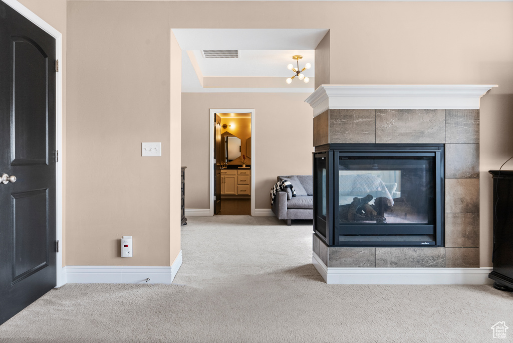 Room details with carpet floors, a notable chandelier, visible vents, a tiled fireplace, and baseboards