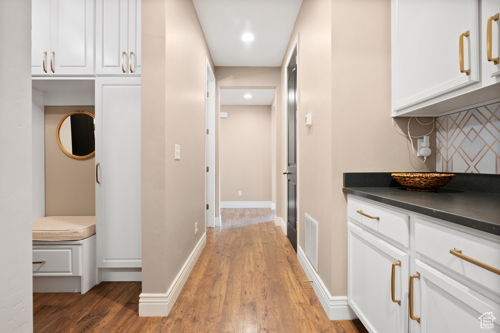 Hallway featuring baseboards, visible vents, wood finished floors, and recessed lighting