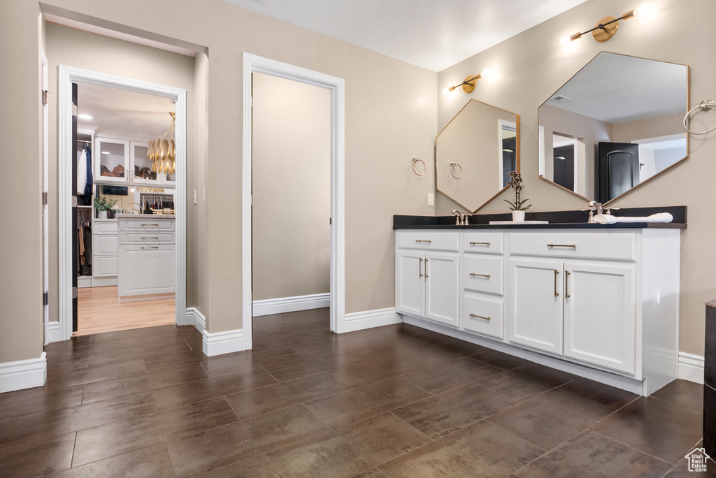 Full bathroom featuring double vanity, a sink, and baseboards