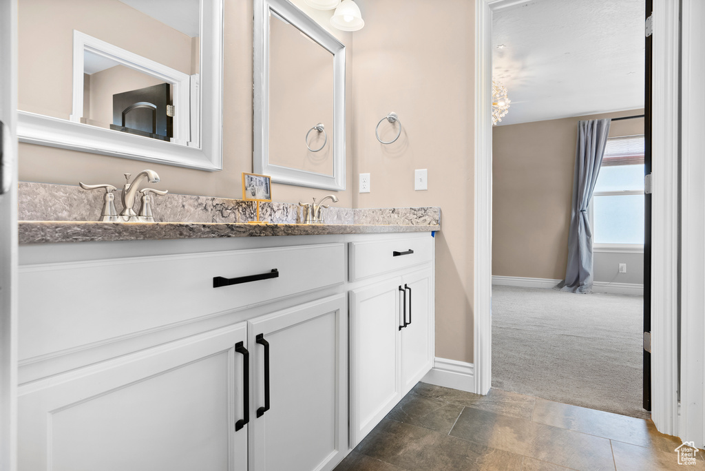 Full bath featuring double vanity, a sink, and baseboards