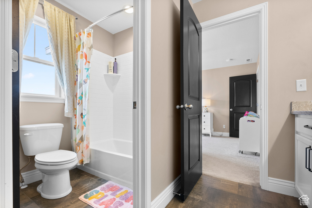 Full bathroom with toilet, shower / tub combo, vanity, and baseboards