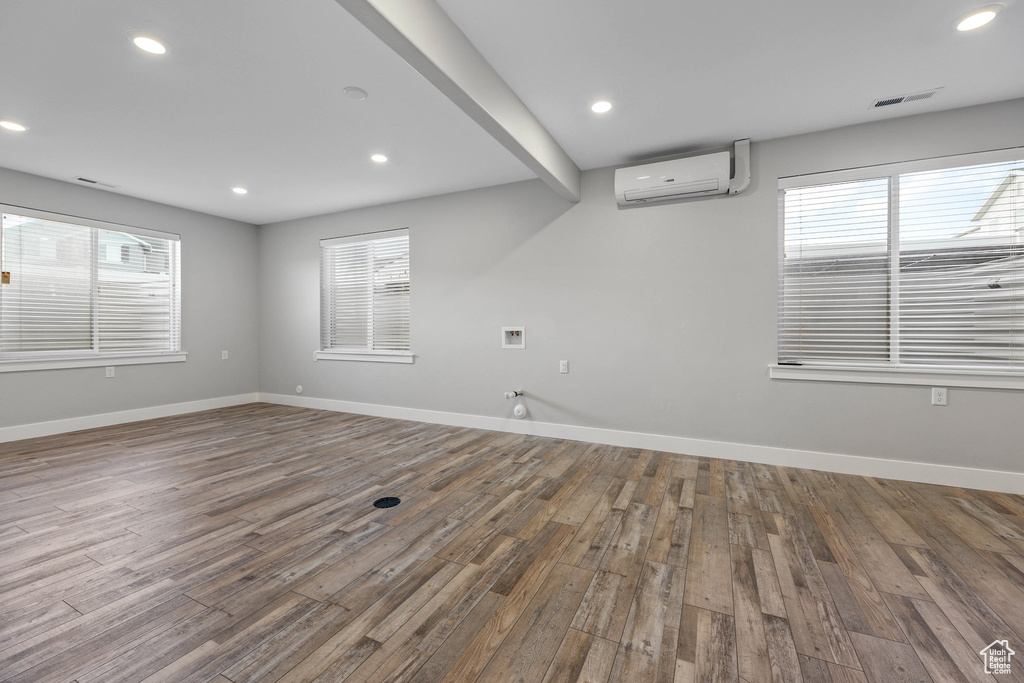 Spare room with recessed lighting, a wall mounted air conditioner, wood finished floors, and baseboards