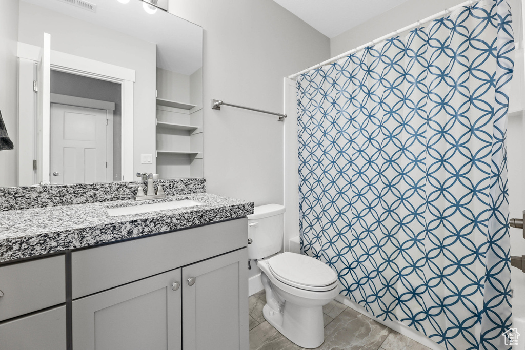 Bathroom featuring toilet, vanity, and a shower with shower curtain